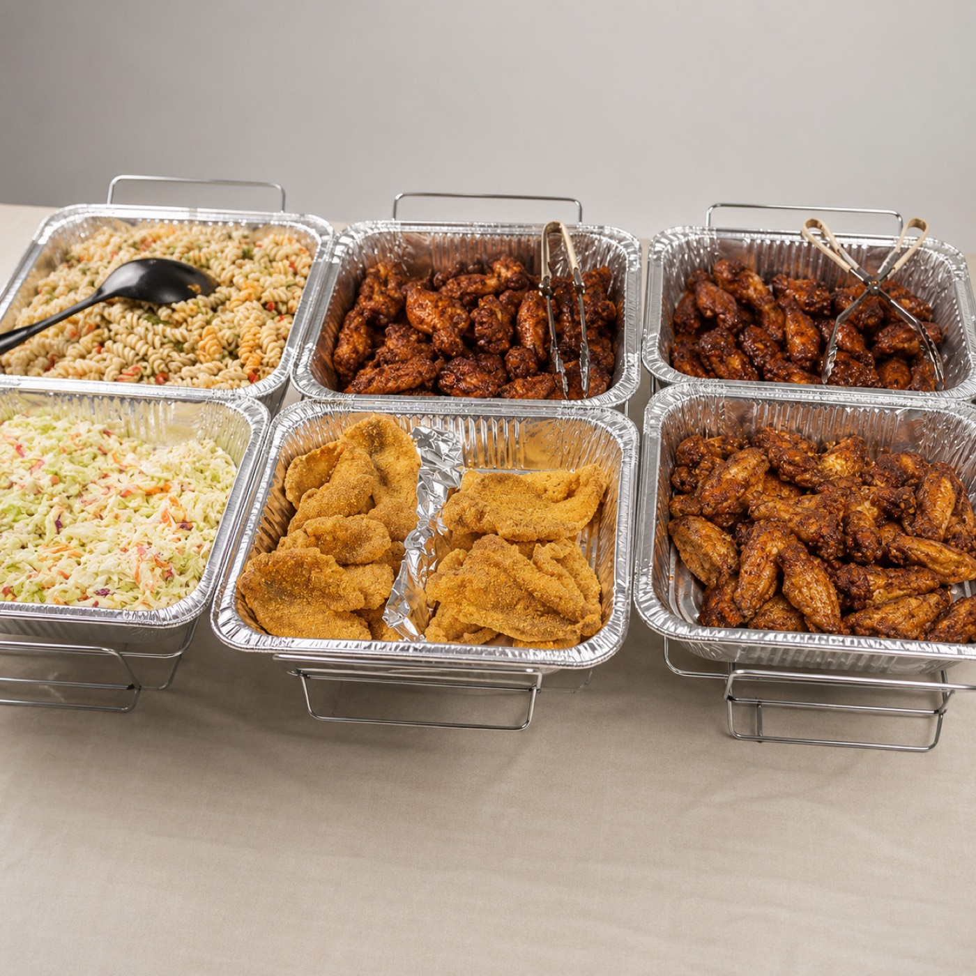 Firebird catering spread with saucy wings, fried fish, pasta salad and coleslaw in serving trays